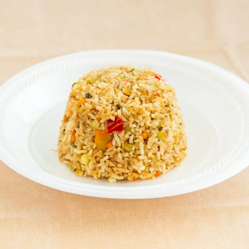 Mound of seasoned rice with mixed vegetables on a white plate.